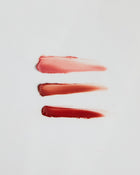 Three swatches of different lip gloss shades on white background