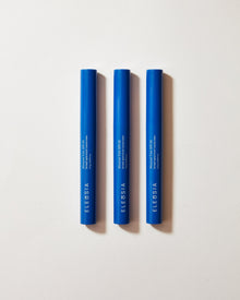 Three blue cosmetic tubes with 'Eleusia' branding on a light gray background